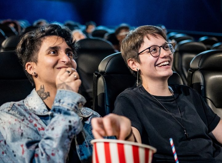 Foto på två transpersoner som sitter i en biosalong. De är på filmkväll med Transammans.
